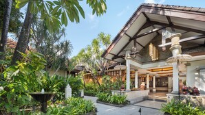 A courtyard with a fountain, lush greenery, and a building with a tiled roof and columns. - Kuta Seaview Beach Resort    (Kuta)