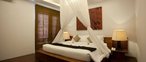 A bedroom with a four-poster bed, a wooden headboard, a bedside table with a lamp, and a wall-mounted air conditioner.