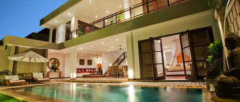 A two-story building with a swimming pool, outdoor seating, and a staircase leading to the upper level.