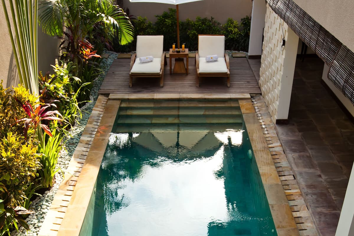 Une piscine rectangulaire dotée d’une terrasse en bois et de chaises longues.