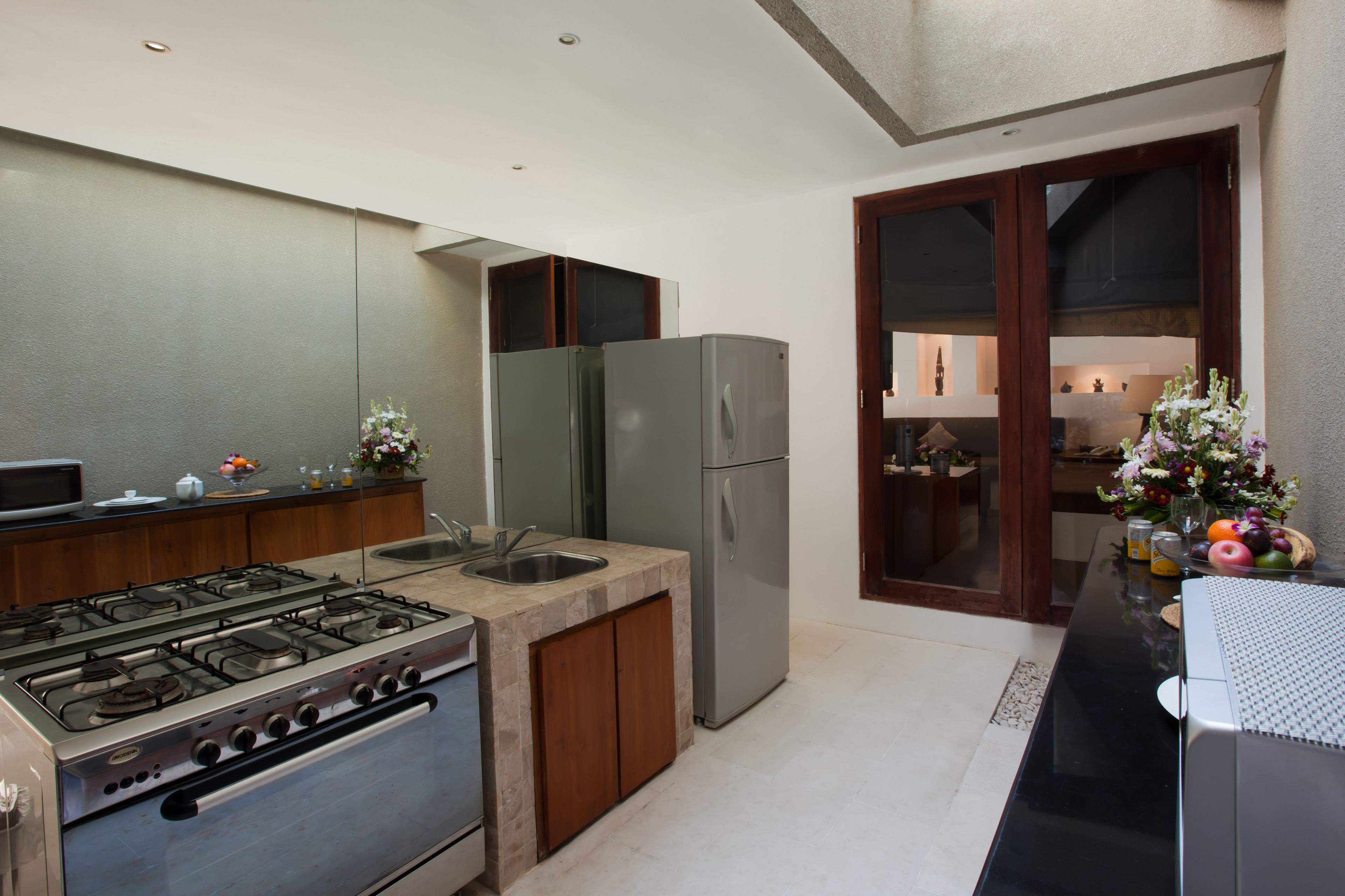 A modern kitchen with a gas stove, stainless steel refrigerator, and wooden cabinets.