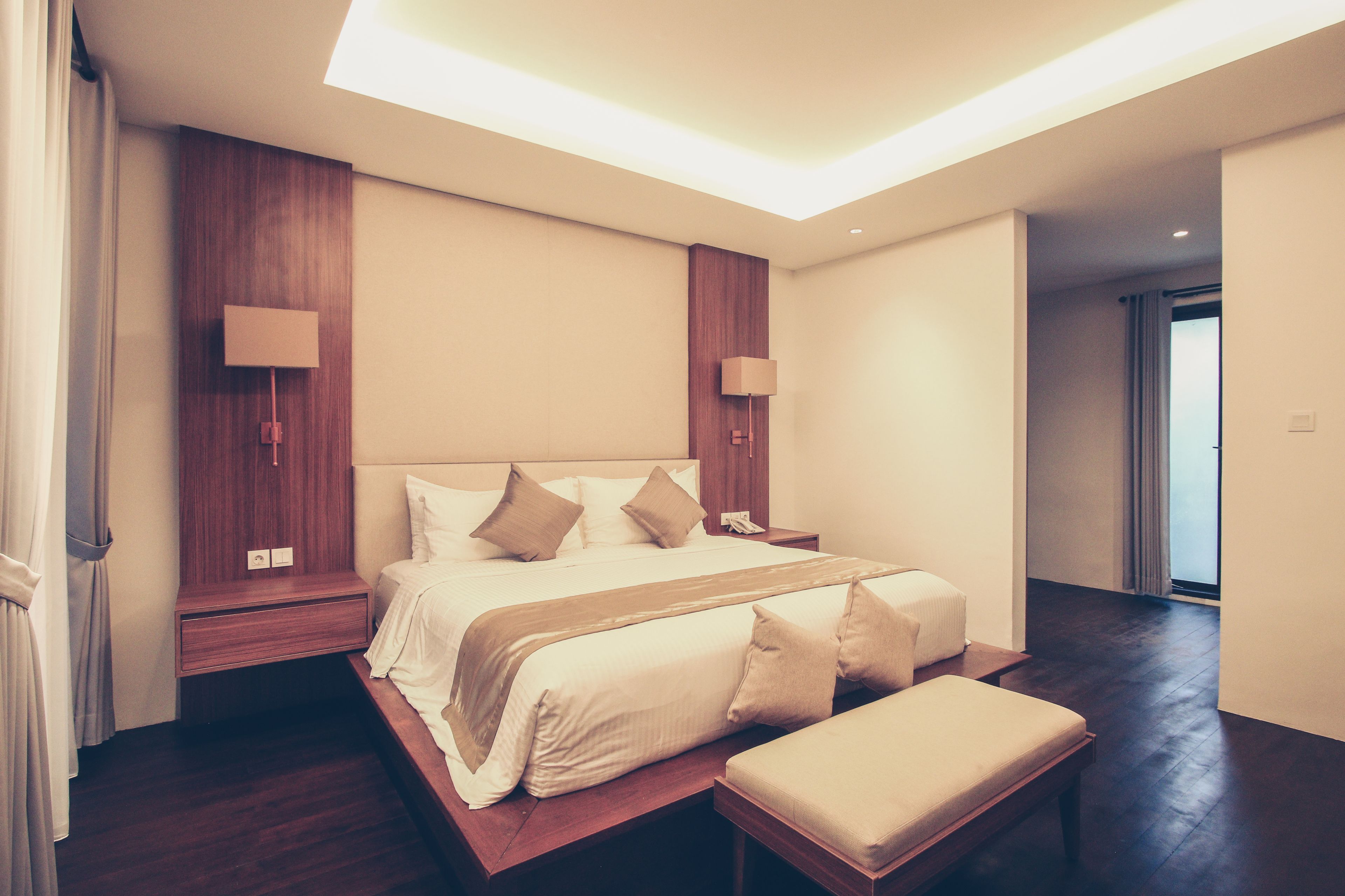 A modern hotel room with a large bed, bedside tables, a bench, and a skylight.