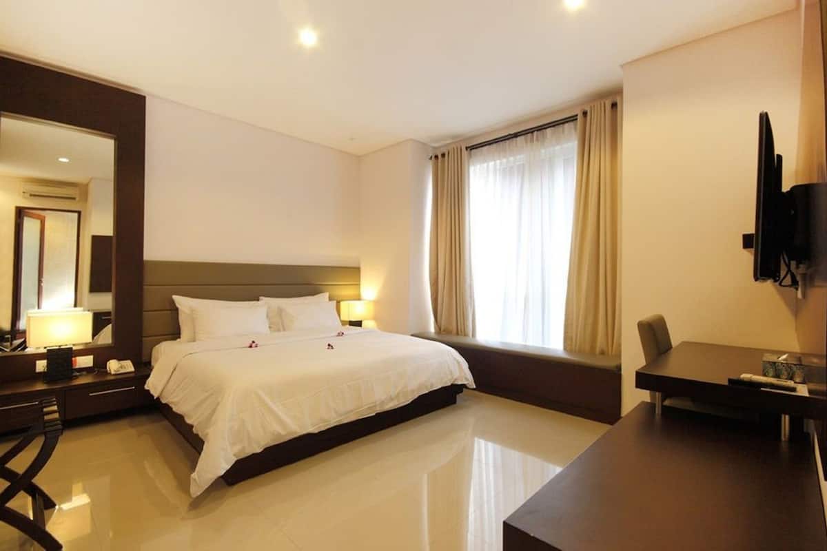 Une chambre d’hôtel avec un grand lit, des tables de chevet, un bureau et une télévision.