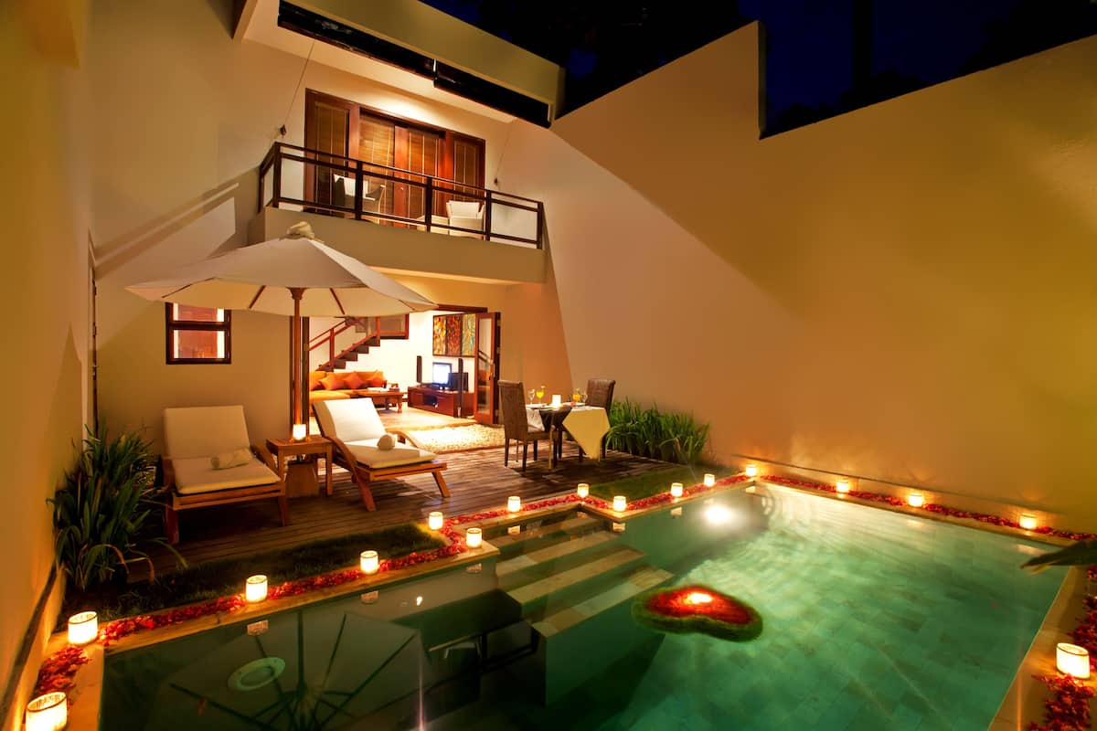 Un espace piscine aménagé sur le toit, doté d’une balustrade en verre, de chaises longues et d’un coin repas avec une table et des chaises.