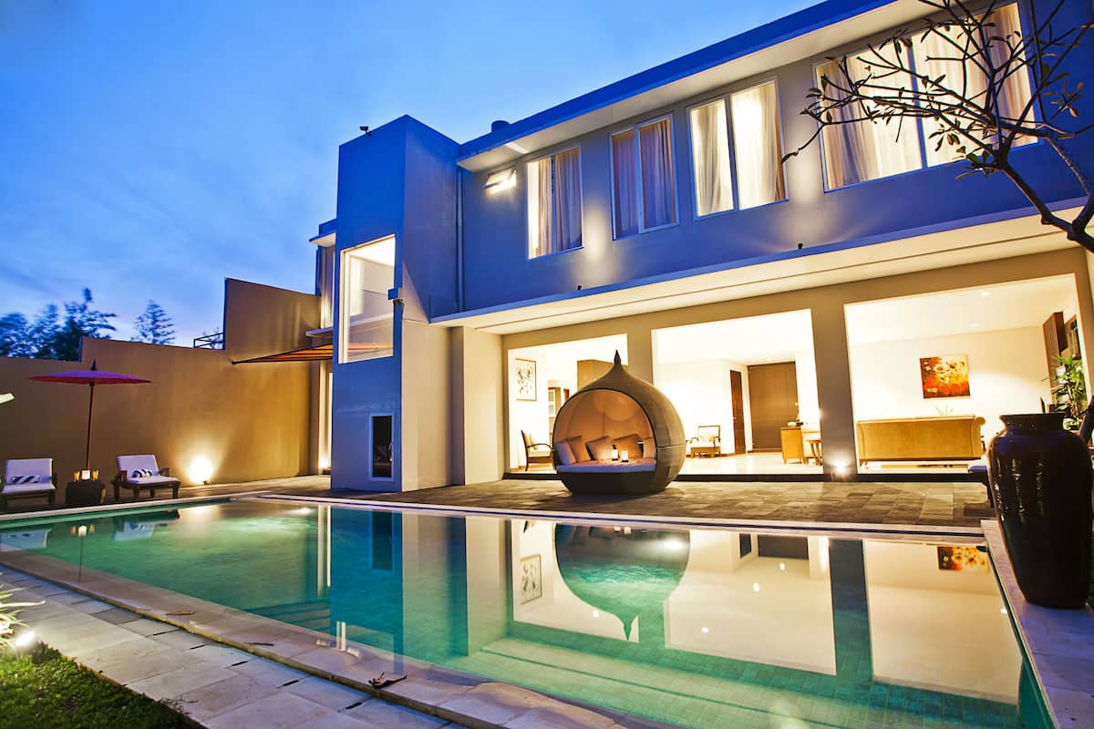 Une maison moderne dotée d’une piscine, d’un jacuzzi et d’un intérieur bien éclairé.