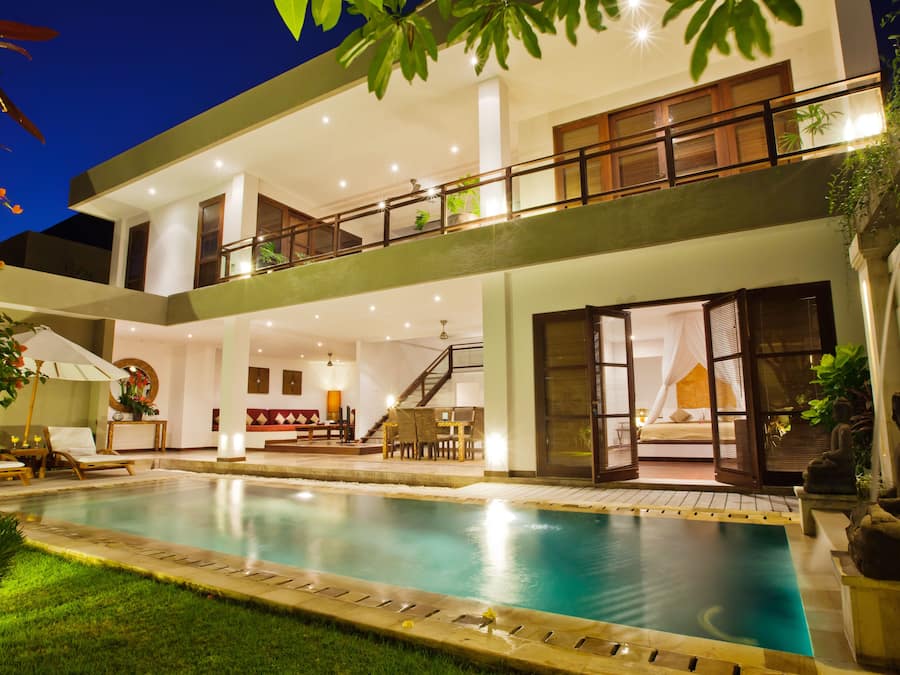 Uma casa moderna de dois andares, com piscina, varanda e escadaria que leva ao andar superior.