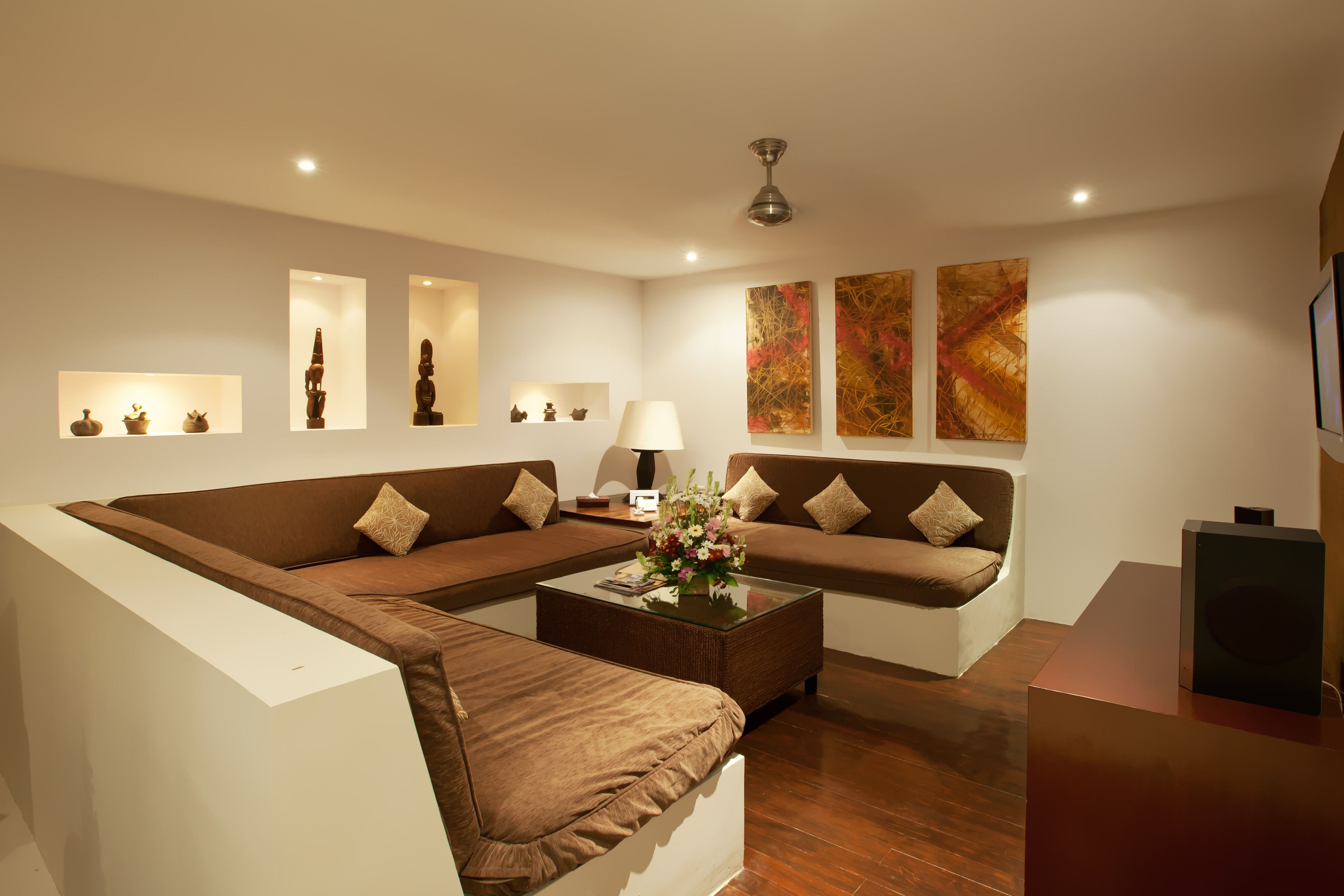 A modern living room with a sectional sofa, a glass coffee table, and wall-mounted artwork.