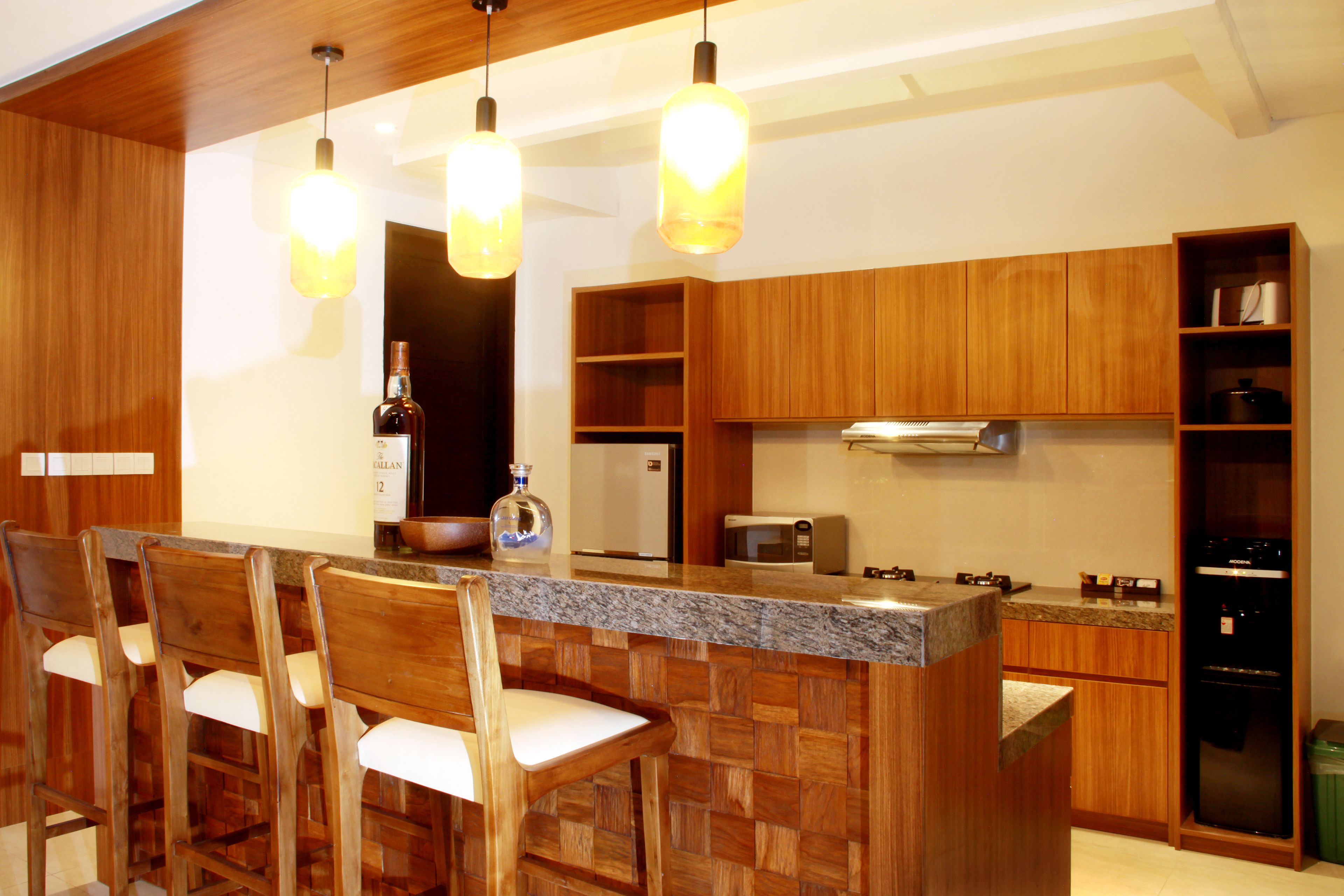 A kitchen with wooden cabinets, a granite countertop, and a bar area with bar stools.