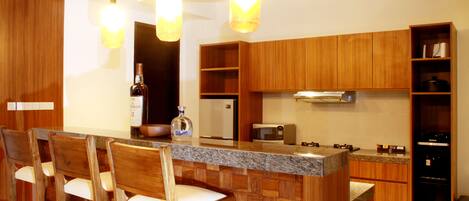 A kitchen with wooden cabinets, a granite countertop, and a bar area with bar stools.