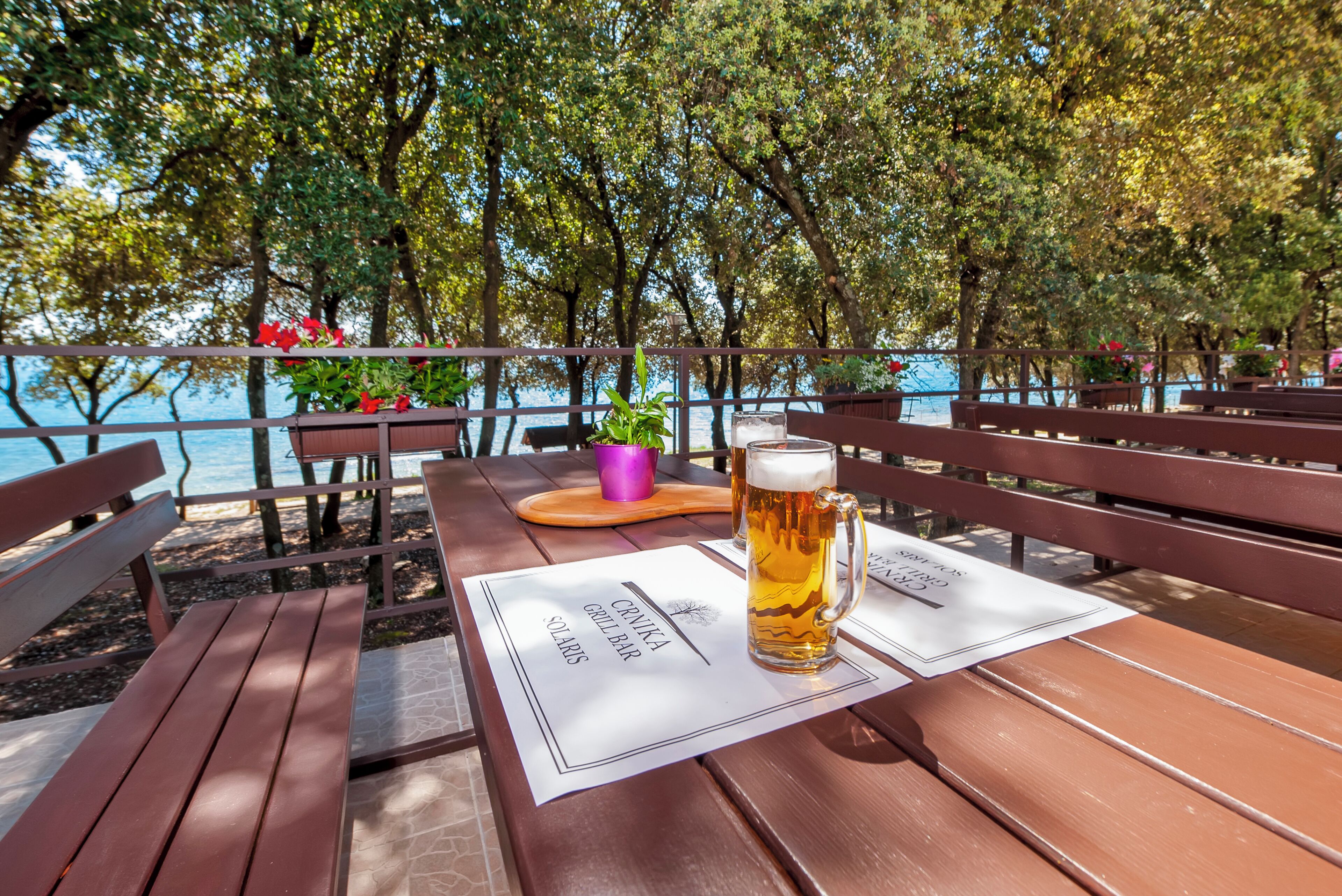 Un banc en bois, avec une chope de bière et un menu, dans un restaurant en bord de mer.