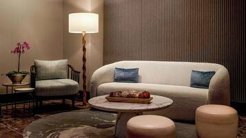 A cozy seating area with a sofa, armchair, and ottoman, a small table with a decorative tray, and a floor lamp.