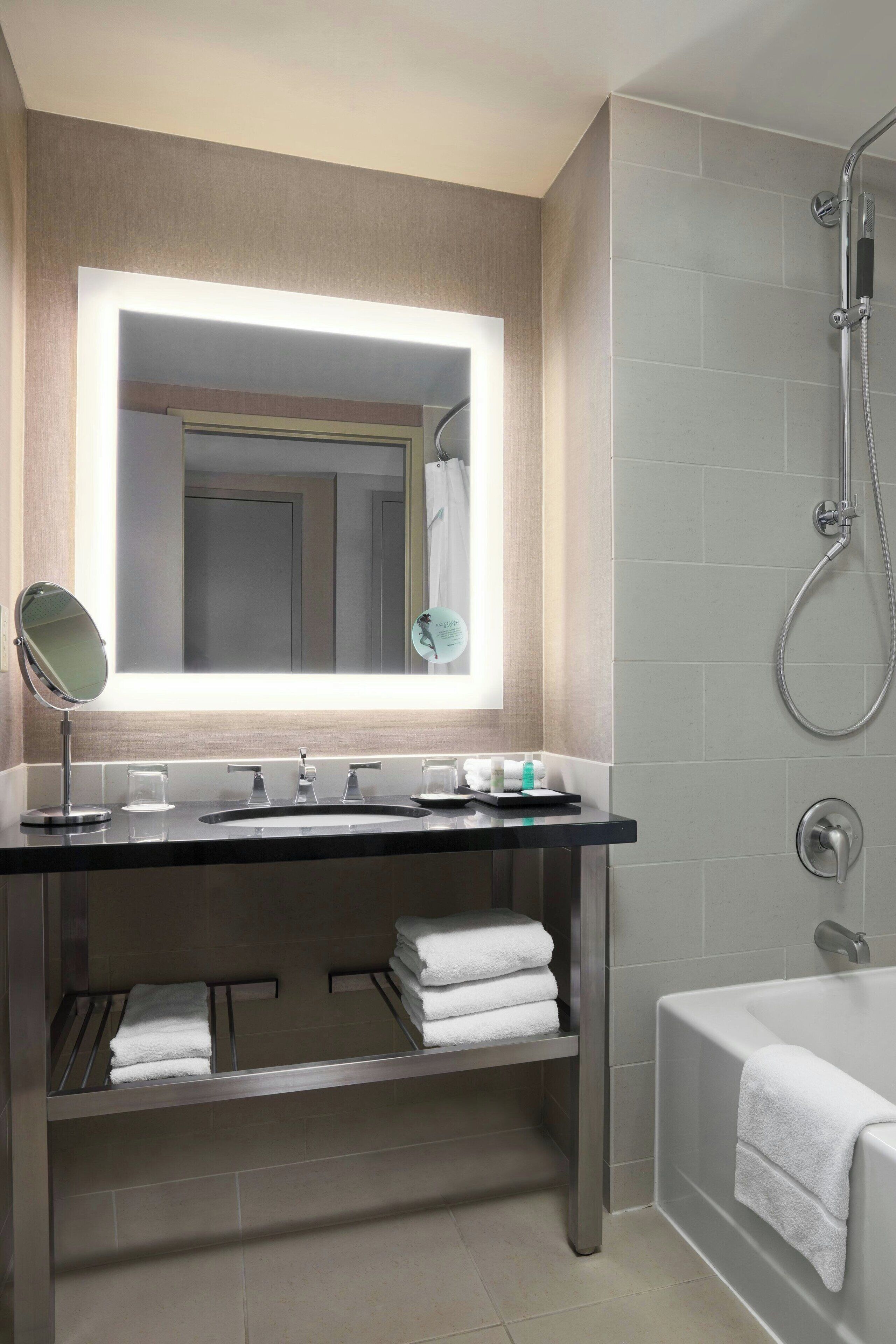 A modern bathroom with a vanity, mirror, sink, and shower.