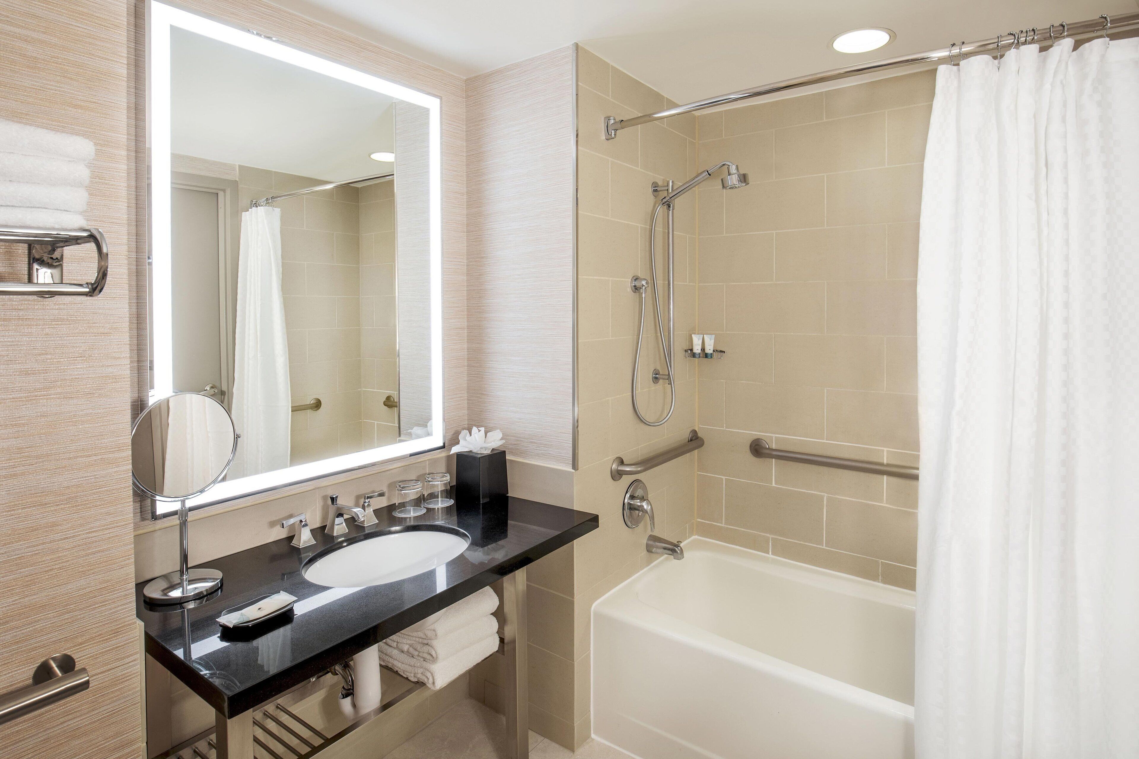 Un baño moderno con un espejo grande, un lavabo, una bañera y una ducha.