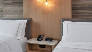 Habitación de hotel con dos camas, una mesita de noche con un teléfono y un dispositivo Sony, y una pared con textura decorativa.