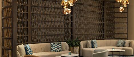 A modern lounge area with sofas, chairs, and a patterned wall.