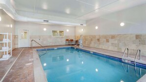 An indoor swimming pool with clear water, tiled walls, and a bench area.