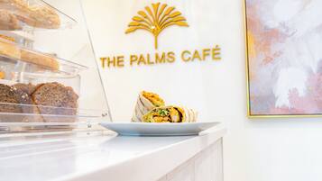 A café counter with pastries and a wrap. The café's logo is displayed above the counter.