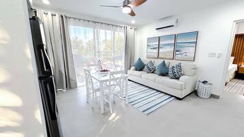 A modern living room with a white sofa, a dining table, and a ceiling fan.