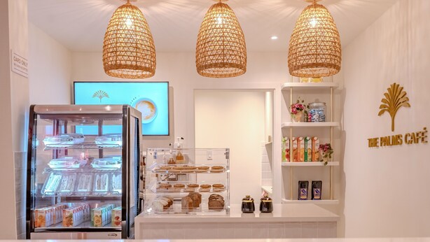 A café interior with a display case of pastries, a refrigerated display, and a shelf with beverages.