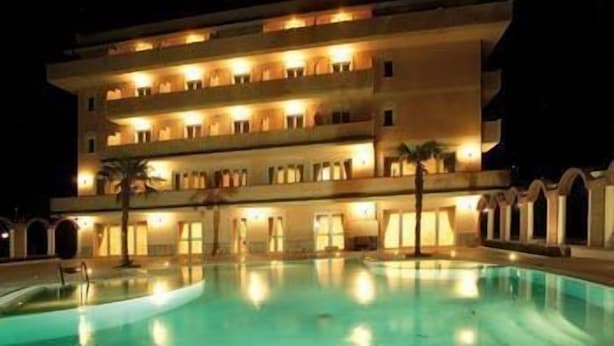 Um hotel de vários andares com piscina na frente.