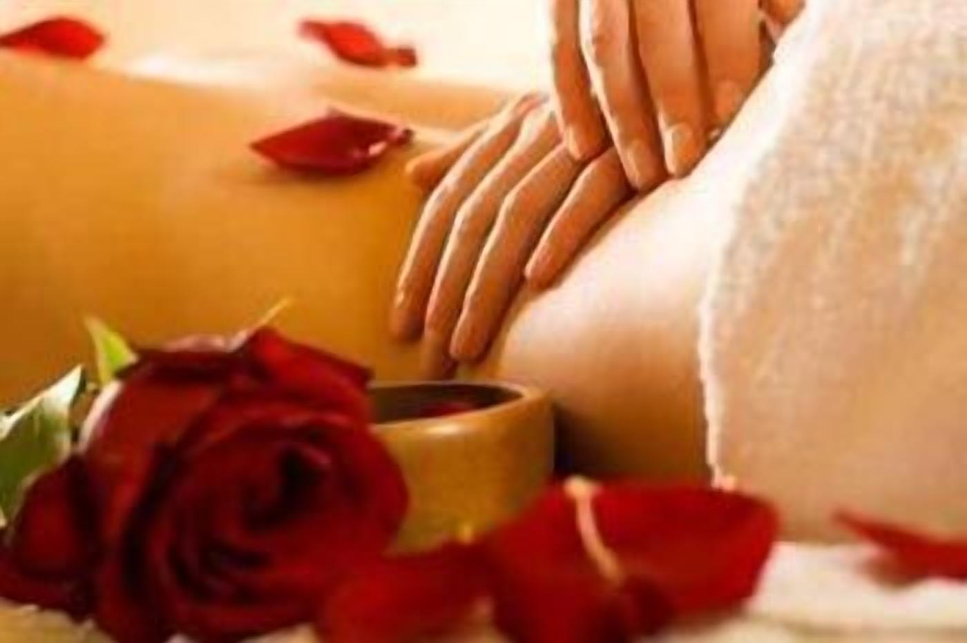 Nahaufnahme einer Massage mit einer roten Rose und einer Kerze.