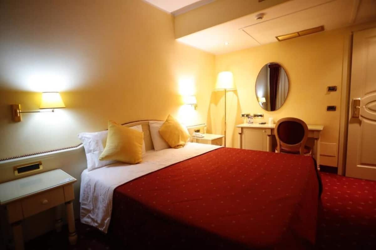 A hotel room with a bed, bedside tables, a desk, and a chair.