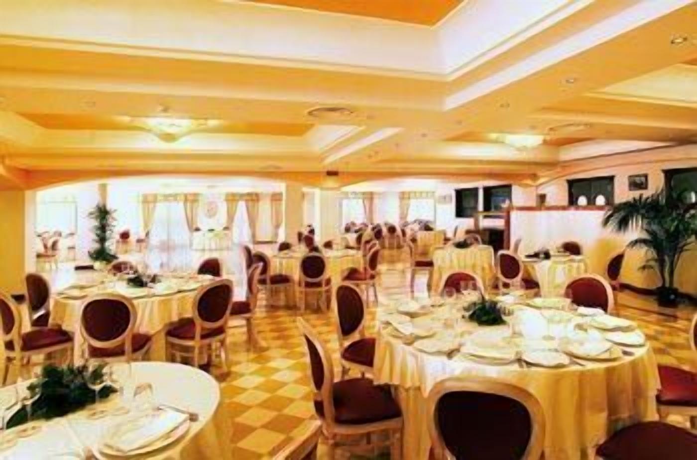 Un gran salón de banquetes con mesas redondas y sillas, dispuestas en filas.