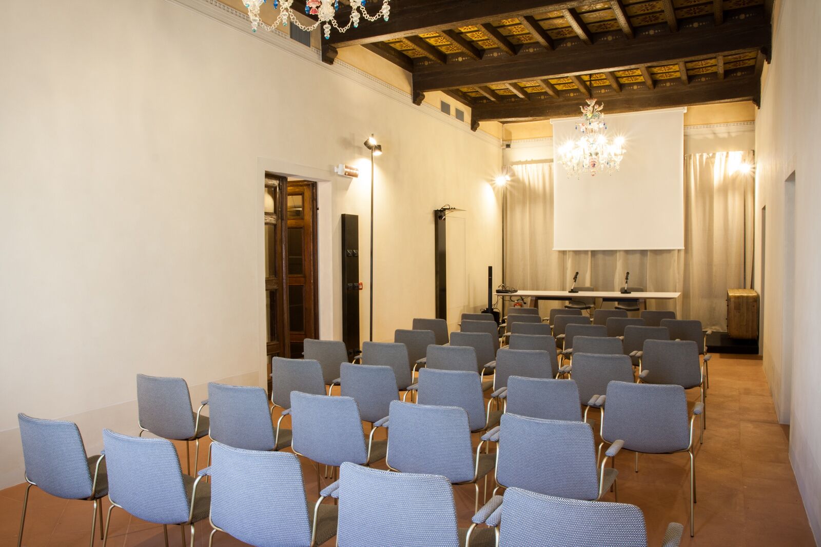 Ein Konferenzraum mit Reihen von Stühlen, einer Projektionsleinwand und einem Rednerpult.