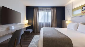 Una camera d'albergo con un letto, una scrivania, una sedia, una televisione e una finestra con tende.