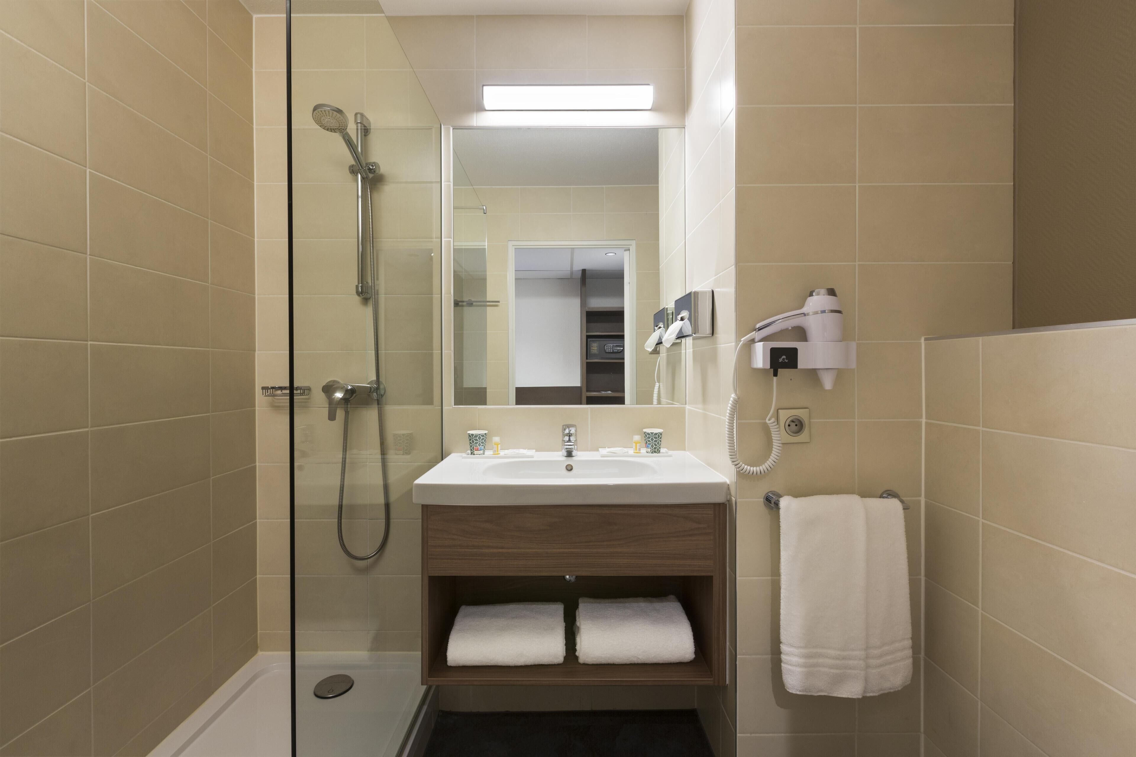 Un baño moderno con ducha de vidrio, un lavabo con espejo y un perchero para toallas.