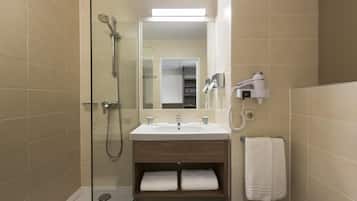 Un baño moderno con ducha de vidrio, un lavabo con espejo y un perchero para toallas.