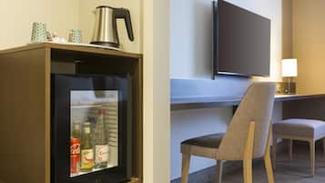 Una camera d'albergo con un minibar, una televisione, una sedia e una scrivania.