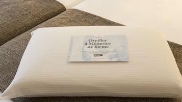 Un coussin blanc, orné d’une étiquette, est posé sur un canapé à la texture particulière.