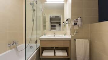 A bathroom with a glass-enclosed shower, a sink with a mirror above it, and a towel rack with a towel.
