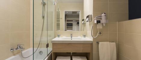 Une salle de bain moderne avec une douche à parois de verre, un lavabo avec un miroir au-dessus et un porte-serviettes.