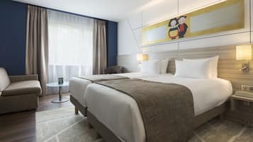 A hotel room with a bed, two bedside tables, a chair, a small table, and a painting on the wall.