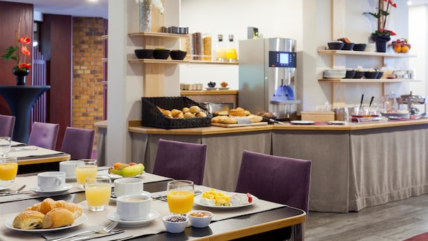 A breakfast buffet with various food items and beverages, a coffee station, and a digital screen displaying information. - Hôtel Kyriad Strasbourg (Lingolsheim)
