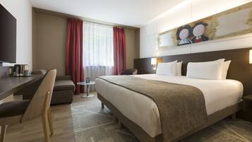 Una habitación de hotel con una cama grande, un escritorio, una silla y un cuadro en la pared.