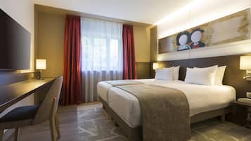 Une chambre d’hôtel avec un lit, un bureau, une chaise et un tableau au mur.