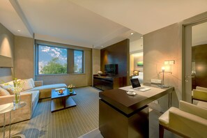 A modern hotel room with a sofa, a coffee table, a desk with a laptop, a TV, and a large window offering a view of the outdoors. - Shanghai Zhangjiang Parkyard Hotel (Shanghai)