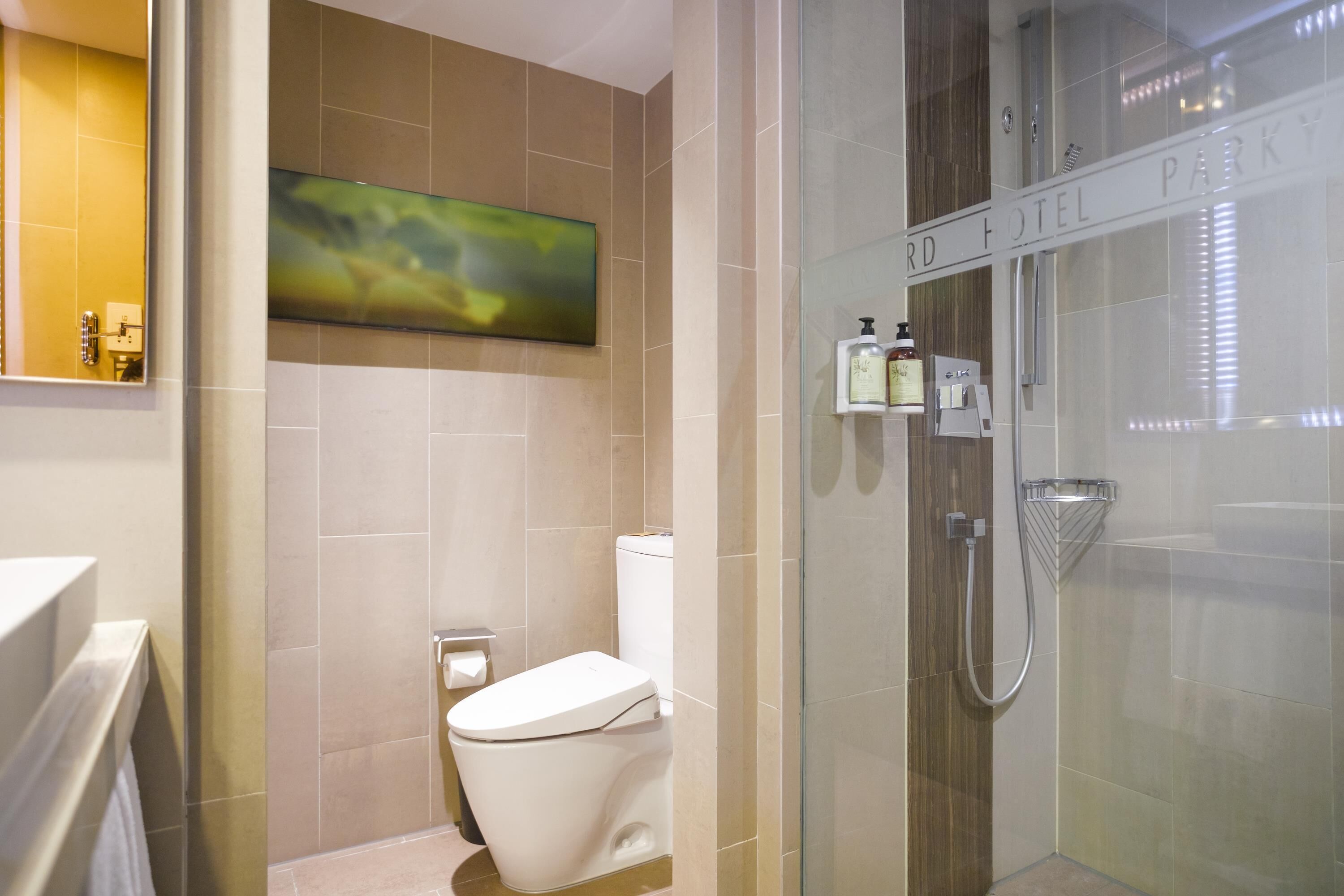 Un baño moderno con cabina de ducha de vidrio, inodoro y espejo montado.