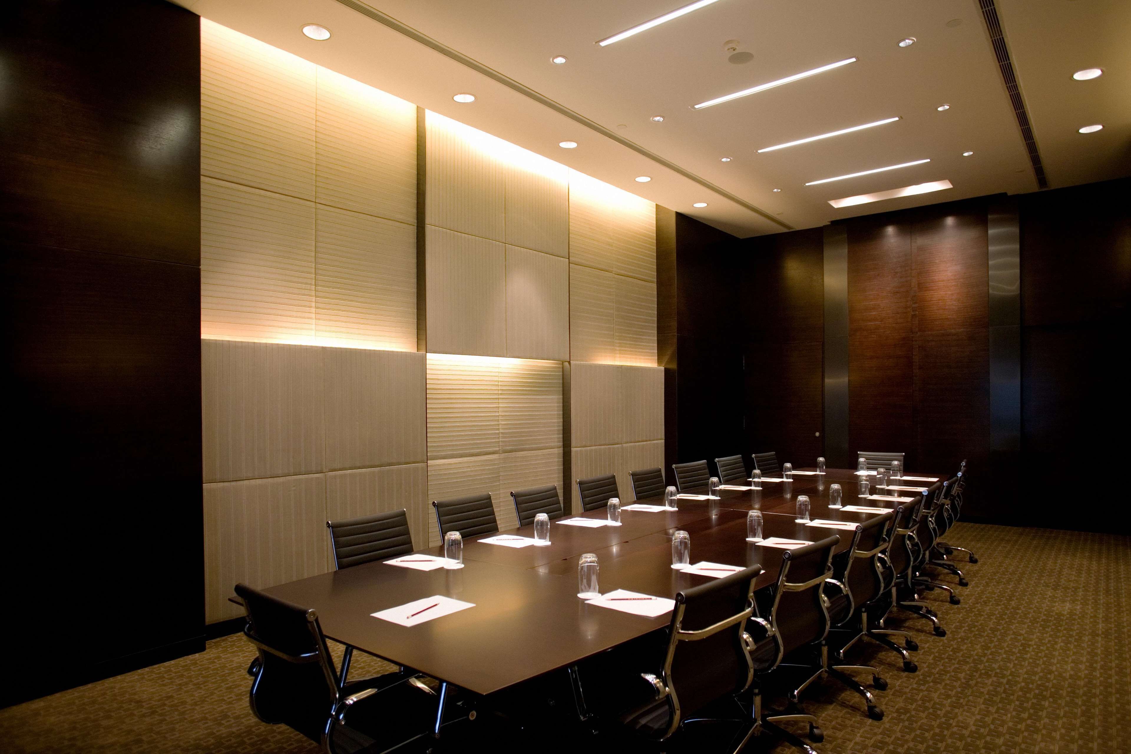 A conference room with a long table, chairs, and a carpeted floor.