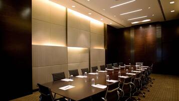 A conference room with a long table, chairs, and a carpeted floor.