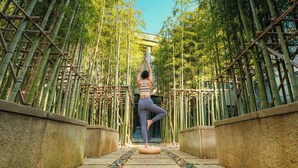 A person performing a yoga pose on a mat in a bamboo forest pathway. - Shanghai Zhangjiang Parkyard Hotel (Shanghai)