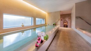 A long, narrow indoor pool with a clear glass barrier, a small statue, and a decorative pink wreath on the edge. - Shanghai Zhangjiang Parkyard Hotel (Shanghai)