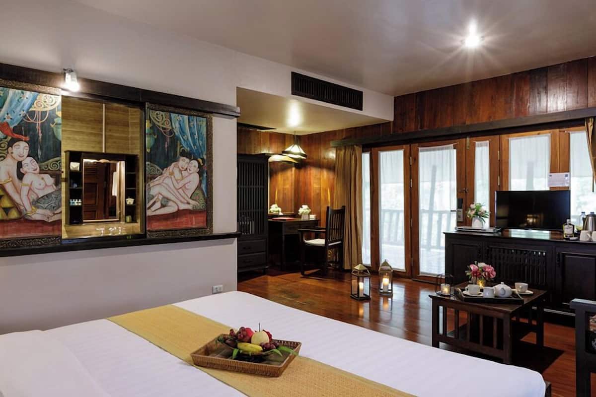 Una habitación de hotel con cama, zona de comedor, televisión y obras de arte en las paredes.