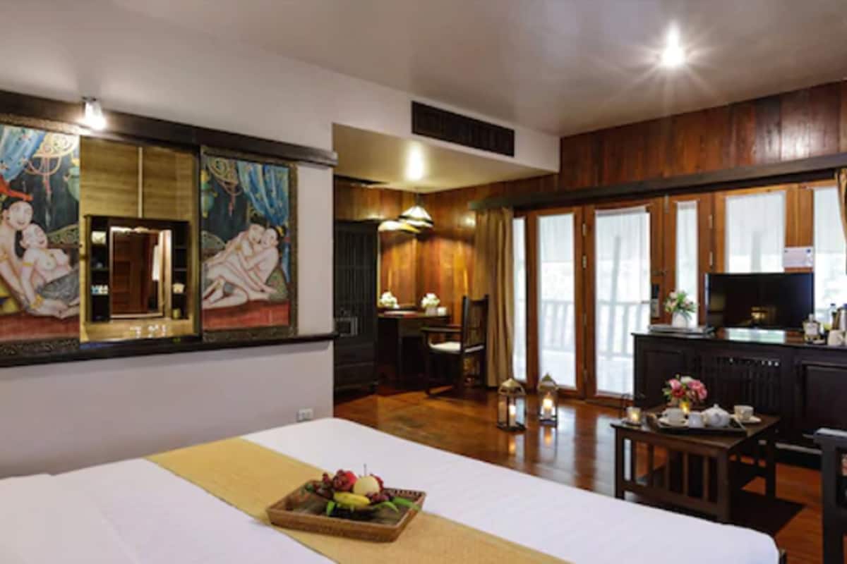 A hotel room with a bed, a dining table with a tray of fruit, a television, and a kitchen area.