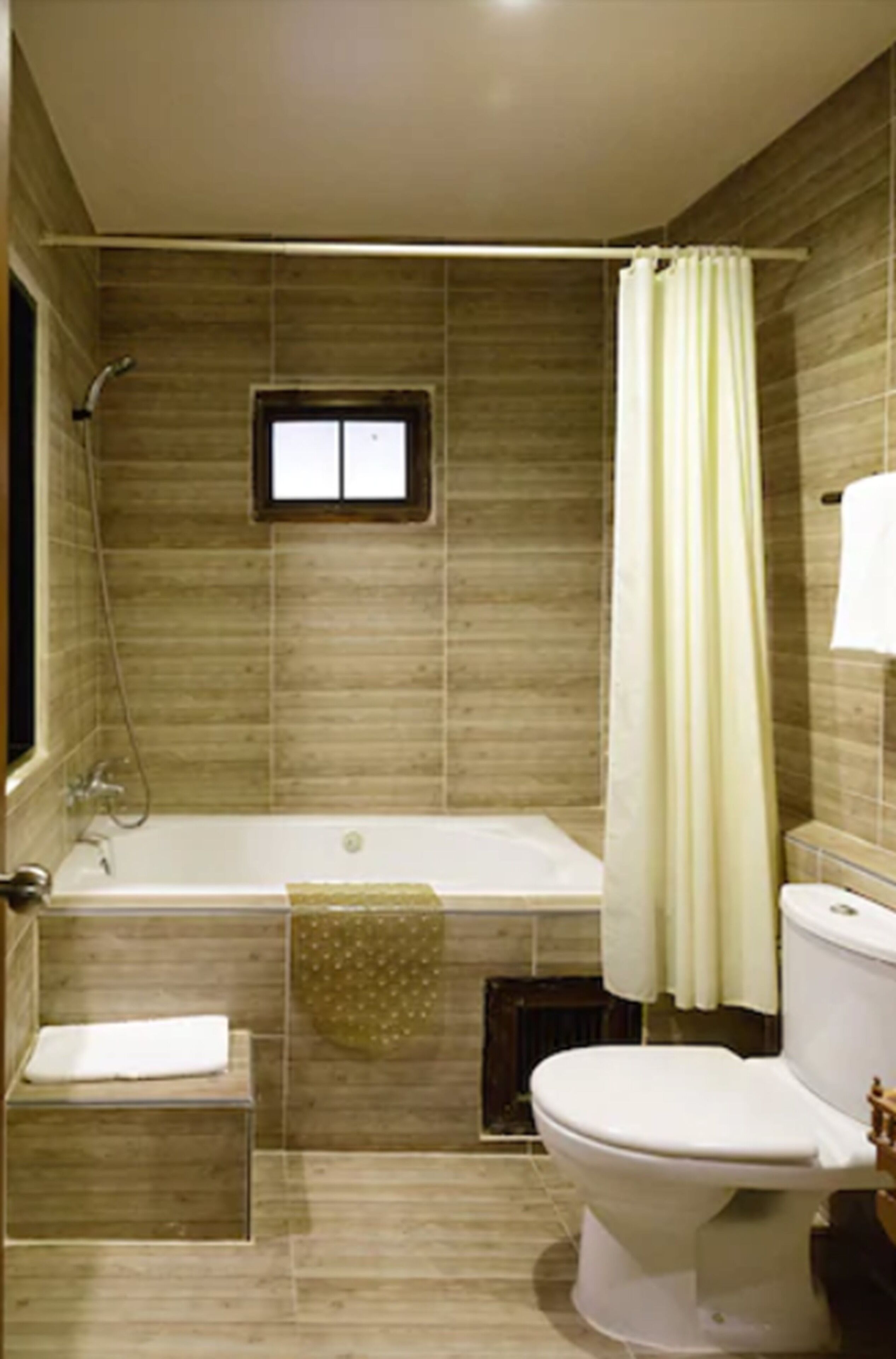 Une salle de bain avec une baignoire, des toilettes et une fenêtre.