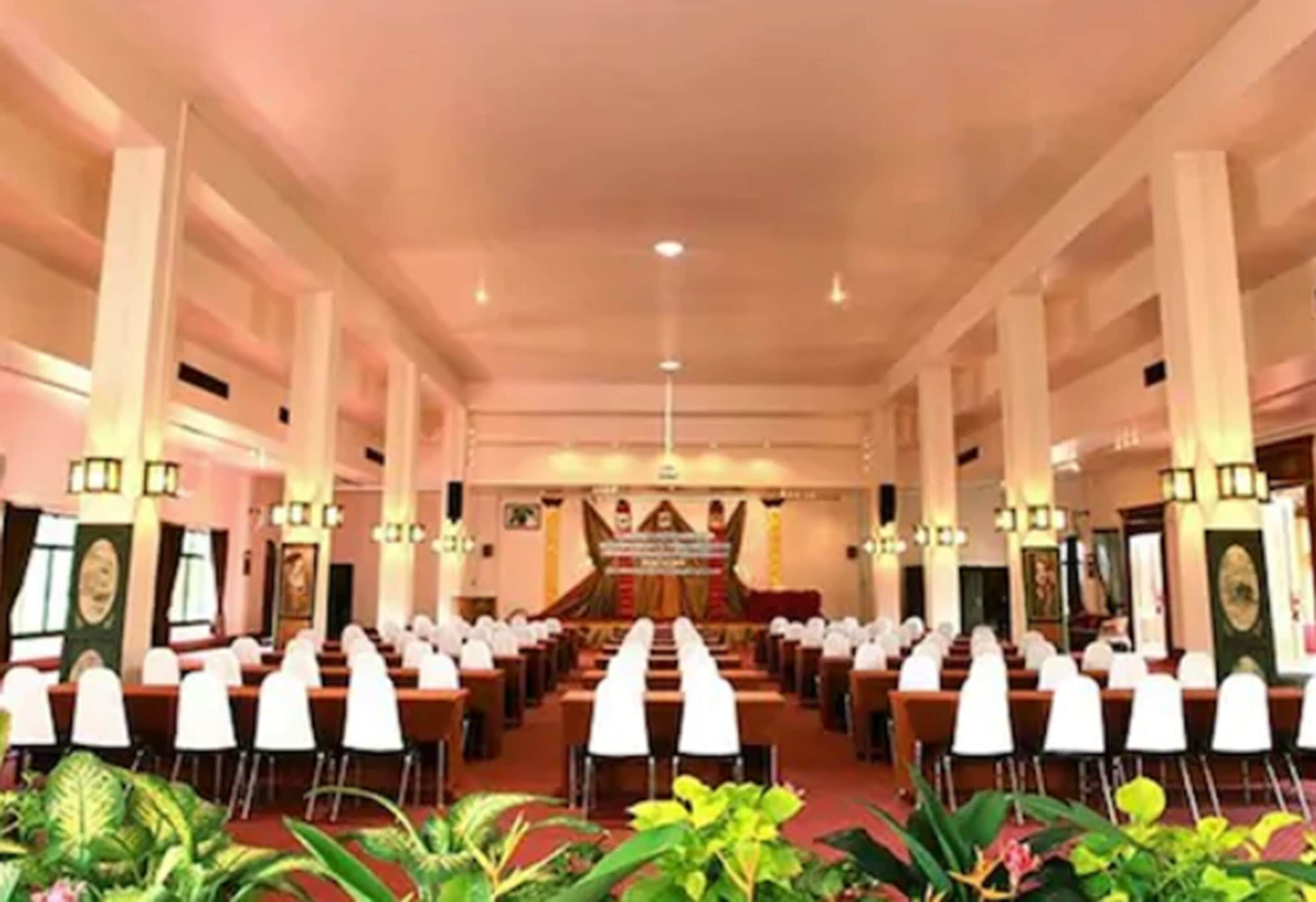 A large hall with rows of white chairs and a stage at the front.