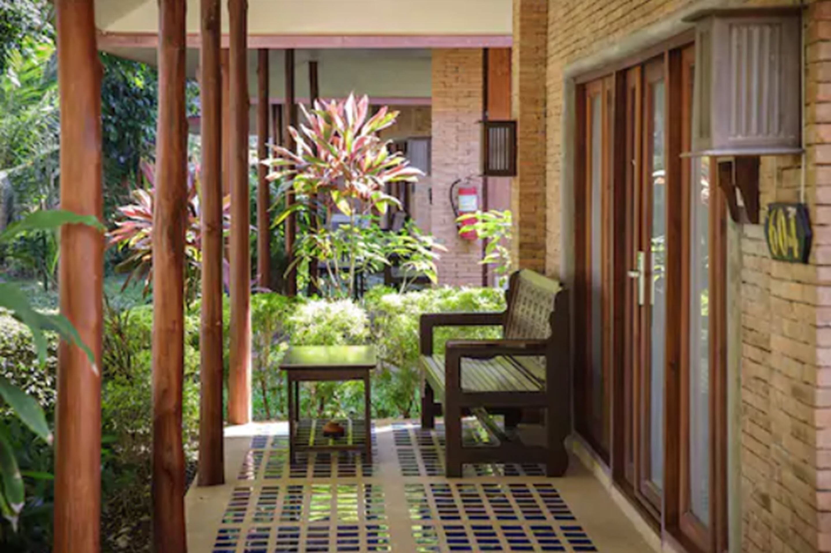 A covered outdoor area with a bench, a small table, and a potted plant.